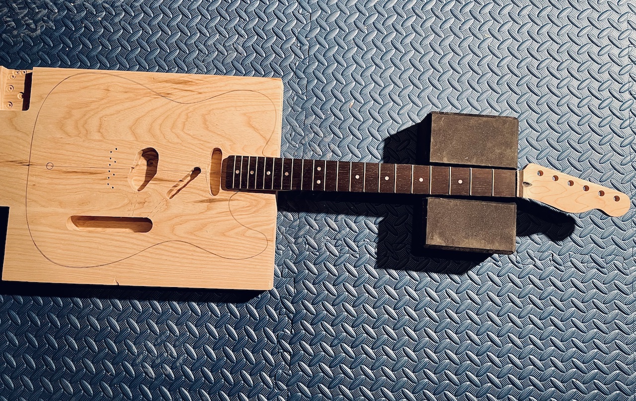 wood guitar blank with routes cut out and the neck in position